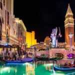 People riding in gondolas in Las Vegas at night surrounded by lights.