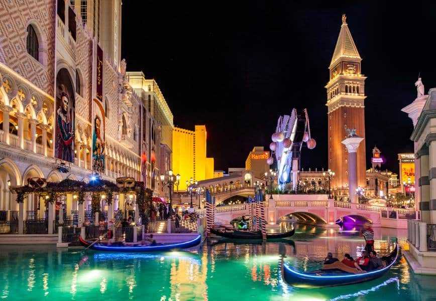 People riding in gondolas in Las Vegas at night surrounded by lights.